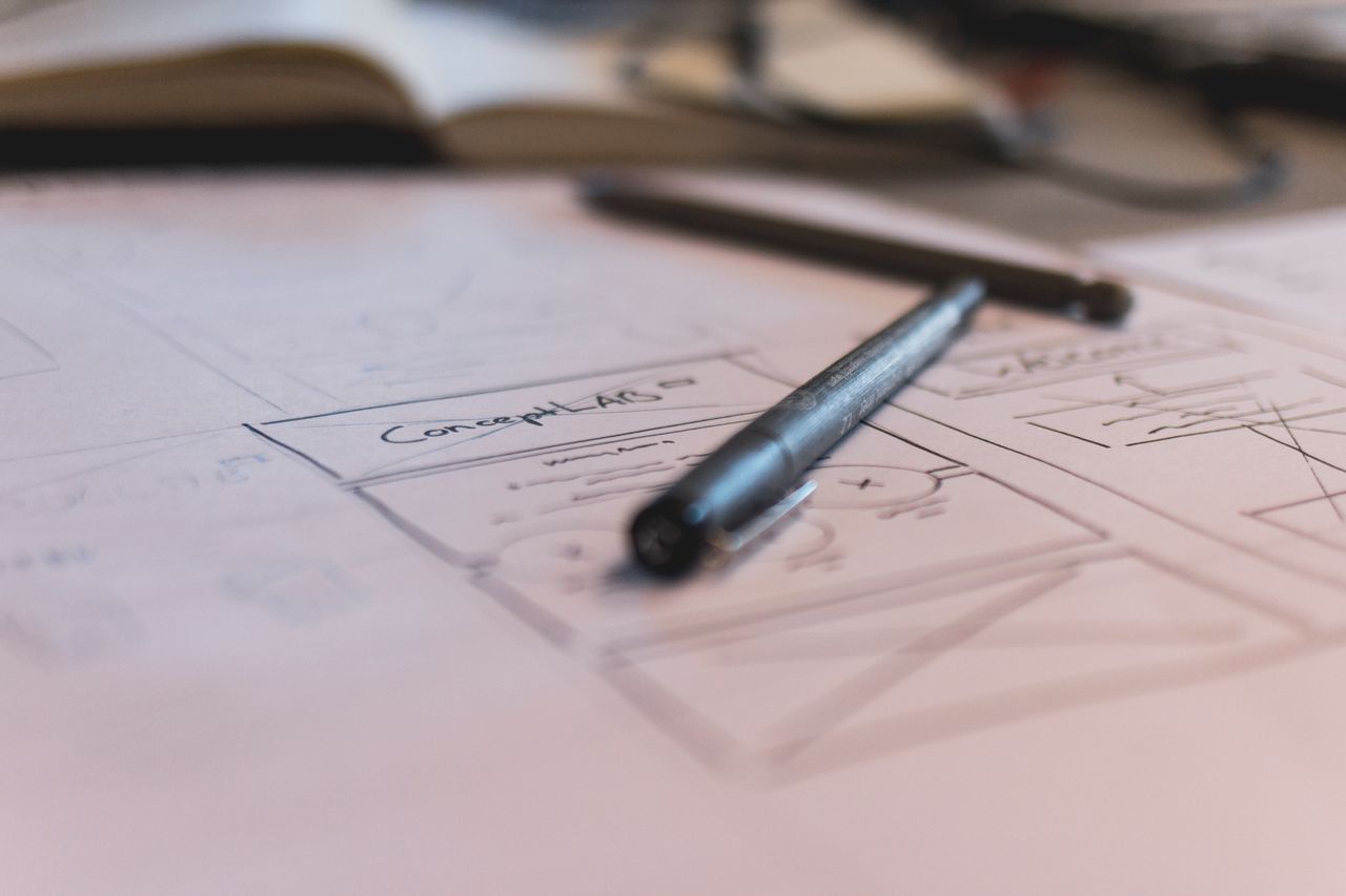 about-us-01 A sketch with notes and a pen on paper. Ideal for planning or design concepts.